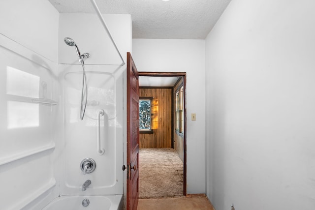 bathroom featuring wooden walls, shower / bath combination, and a textured ceiling