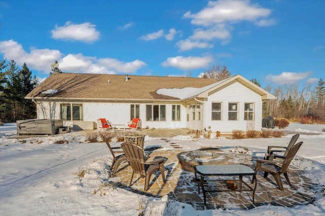 snow covered house featuring a hot tub, an outdoor fire pit, and a patio area