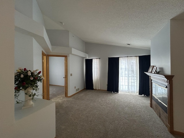 carpeted living room with a textured ceiling, lofted ceiling, and a tiled fireplace