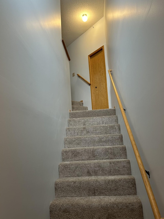 stairs featuring a textured ceiling