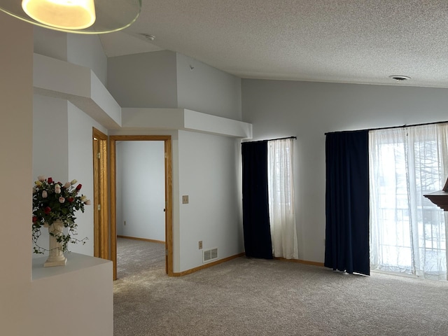 carpeted empty room with a textured ceiling and high vaulted ceiling