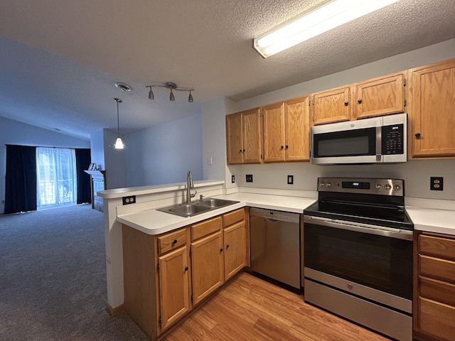 kitchen featuring kitchen peninsula, light wood-type flooring, stainless steel appliances, sink, and pendant lighting