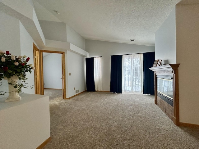 unfurnished living room featuring a textured ceiling, light colored carpet, vaulted ceiling, and a tiled fireplace