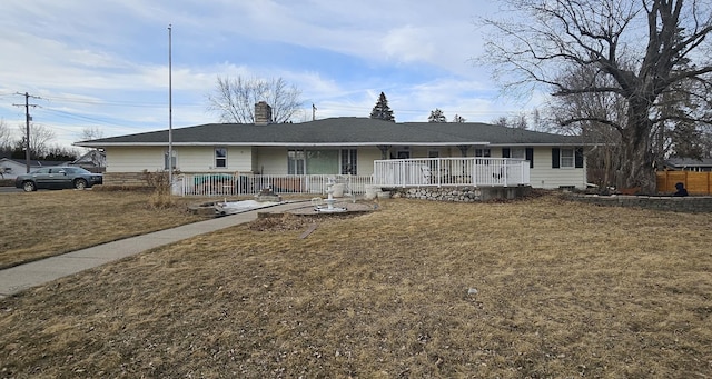 single story home with a front yard, covered porch, and a chimney