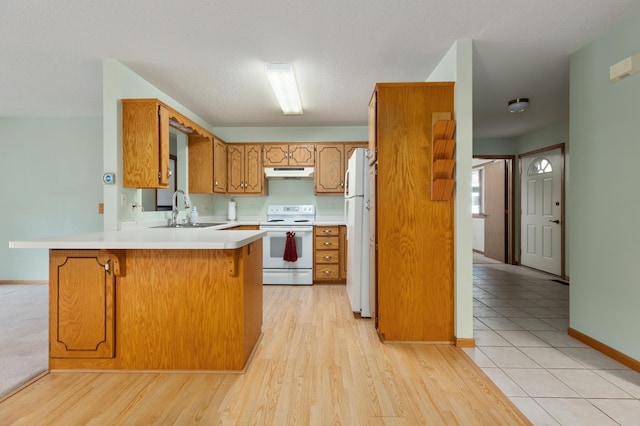 kitchen featuring sink, kitchen peninsula, a textured ceiling, white appliances, and light wood-type flooring