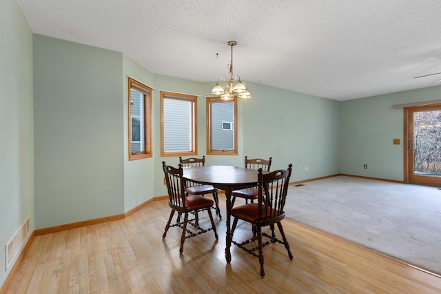 dining room featuring a textured ceiling, light hardwood / wood-style flooring, and ceiling fan with notable chandelier