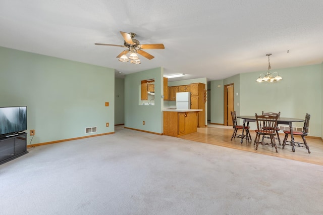 living room with ceiling fan with notable chandelier and light colored carpet