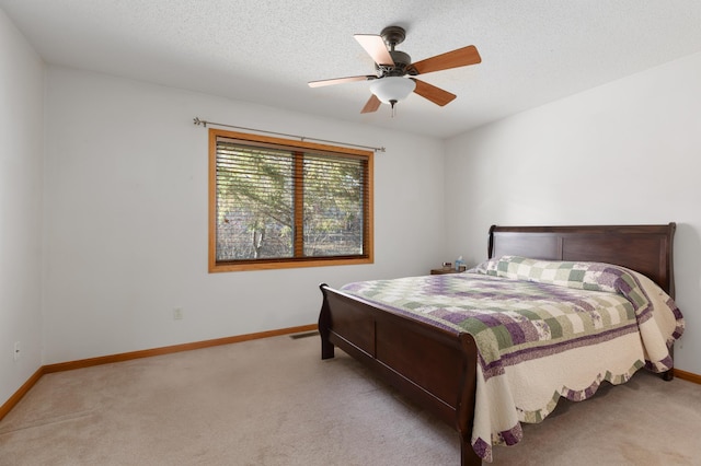 bedroom featuring a textured ceiling, light colored carpet, and ceiling fan