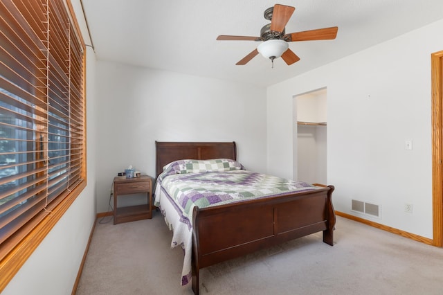 bedroom with ceiling fan, a spacious closet, light carpet, and a closet