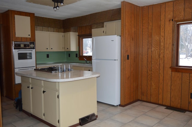 kitchen featuring wood walls, white appliances, sink, decorative backsplash, and a kitchen island