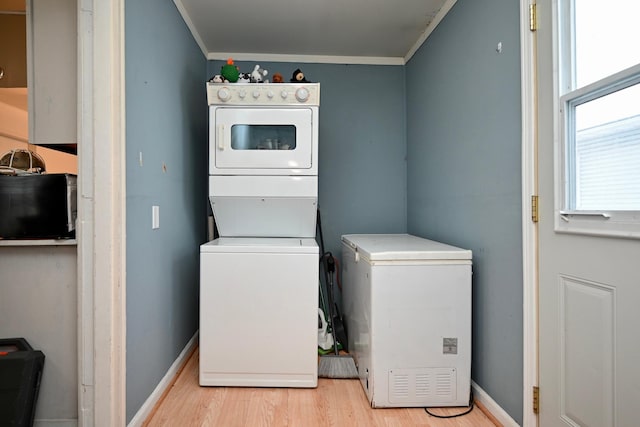 laundry area with light hardwood / wood-style flooring, stacked washer and clothes dryer, and ornamental molding