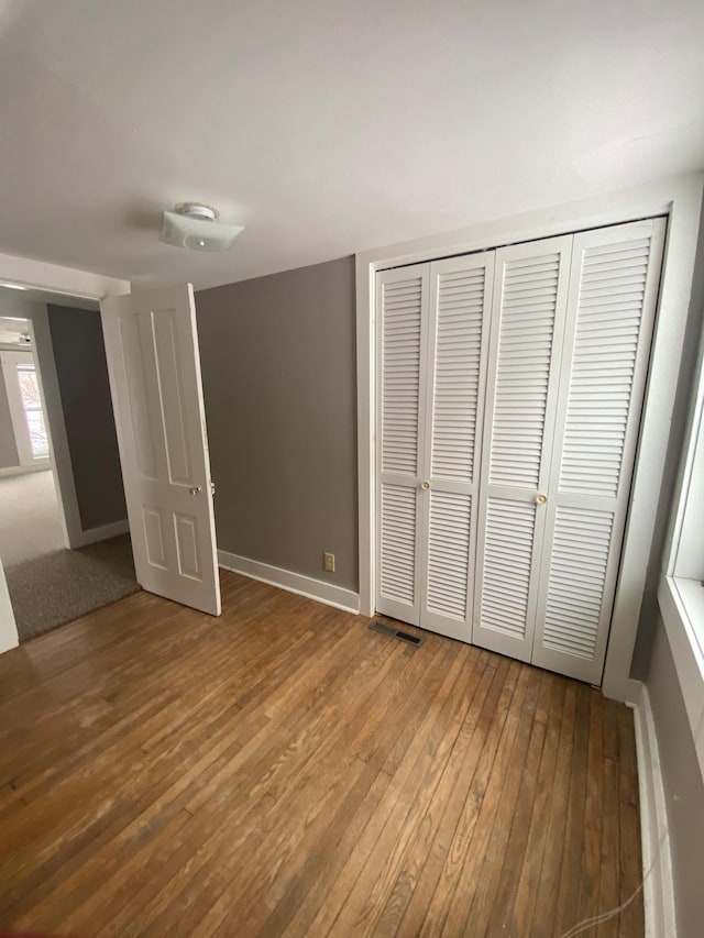 unfurnished bedroom featuring wood-type flooring and a closet