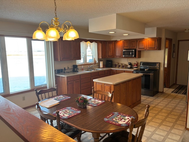 kitchen with sink, hanging light fixtures, an inviting chandelier, a water view, and appliances with stainless steel finishes