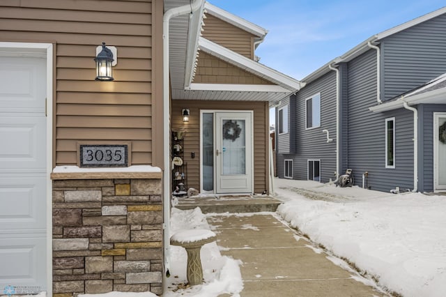 snow covered property entrance with a garage