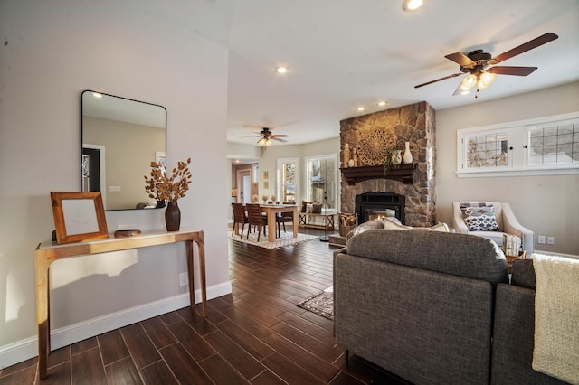 living room featuring ceiling fan, a fireplace, and dark hardwood / wood-style floors