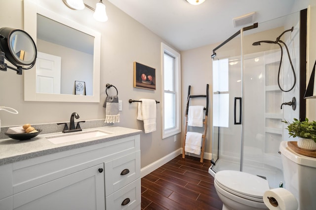 bathroom featuring hardwood / wood-style floors, vanity, a shower with shower door, and toilet