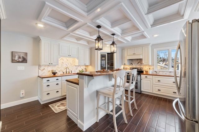 kitchen featuring a center island, dark wood-type flooring, wooden counters, appliances with stainless steel finishes, and white cabinetry