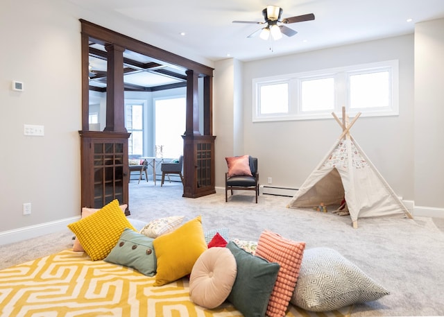 recreation room with light carpet, ceiling fan, a healthy amount of sunlight, and a baseboard heating unit