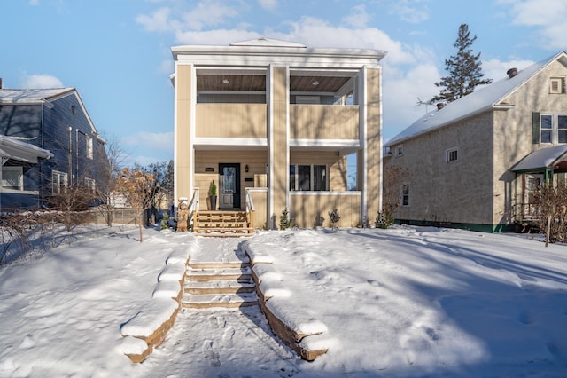 snow covered rear of property featuring a balcony