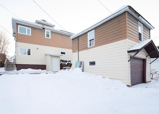 snow covered back of property featuring a garage