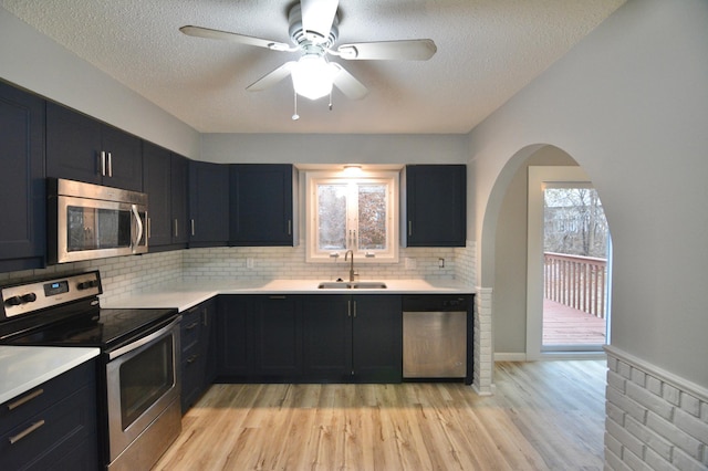 kitchen with sink, ceiling fan, light wood-type flooring, a textured ceiling, and stainless steel appliances