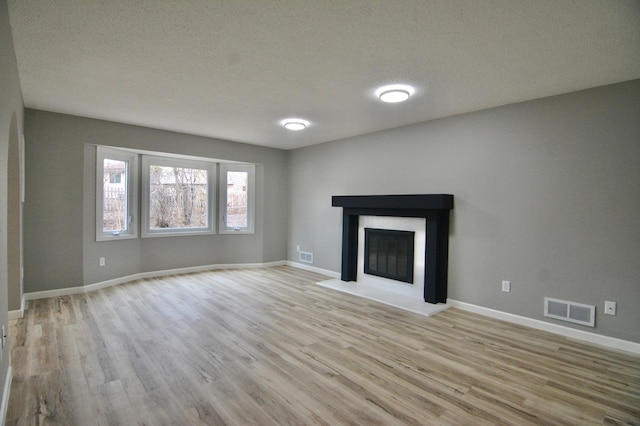 unfurnished living room featuring light hardwood / wood-style floors and a textured ceiling