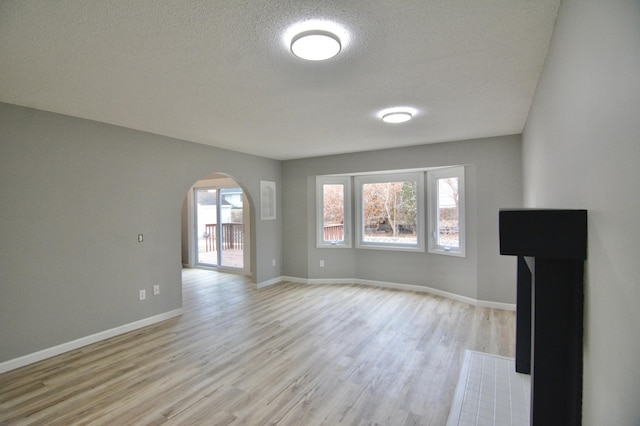 unfurnished living room with light hardwood / wood-style floors and a textured ceiling