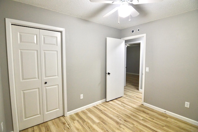 unfurnished bedroom featuring ceiling fan, light hardwood / wood-style floors, a textured ceiling, and a closet