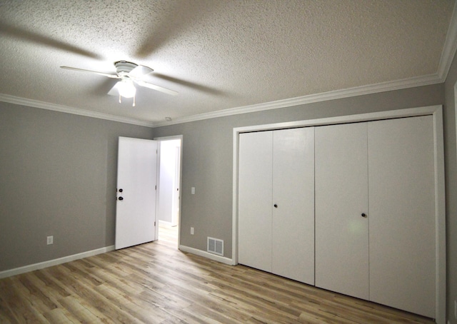 unfurnished bedroom featuring ceiling fan, crown molding, a textured ceiling, a closet, and light wood-type flooring