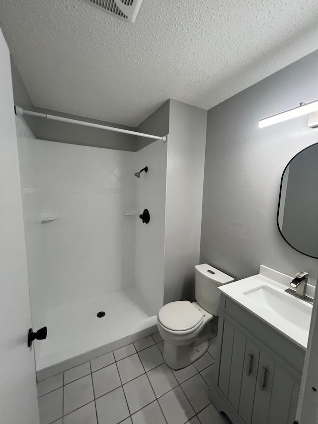 bathroom featuring walk in shower, tile patterned flooring, a textured ceiling, toilet, and vanity