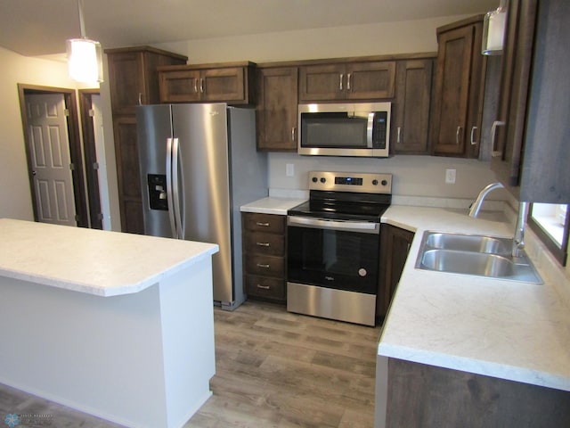 kitchen with pendant lighting, sink, light hardwood / wood-style flooring, appliances with stainless steel finishes, and dark brown cabinets