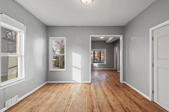 unfurnished room with a textured ceiling and light wood-type flooring