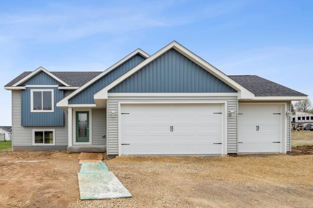 split level home featuring board and batten siding, a shingled roof, an attached garage, and driveway
