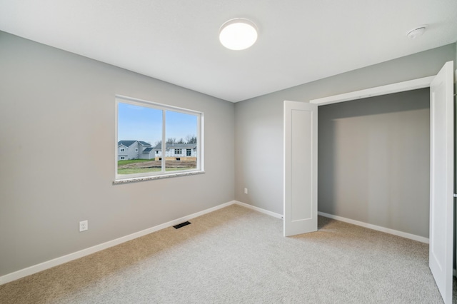 unfurnished bedroom with baseboards, visible vents, and carpet