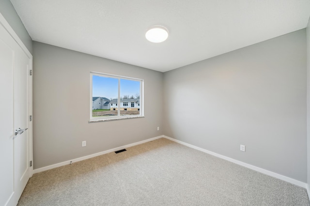 carpeted empty room with visible vents and baseboards