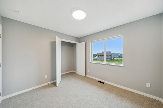 unfurnished bedroom with baseboards, light colored carpet, and visible vents