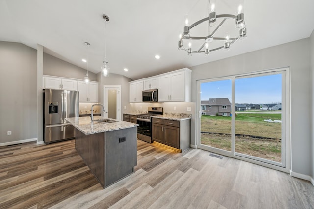 230 Eagle Ridge Dr, Roberts, WI 54023 - kitchen featuring appliances with stainless steel finishes, a chandelier, light wood-type flooring, white cabinetry, and light stone countertops