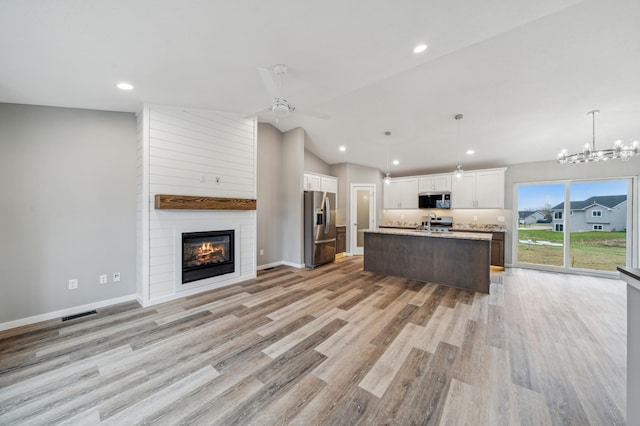 230 Eagle Ridge Dr, Roberts, WI 54023 - kitchen featuring appliances with stainless steel finishes, open floor plan, white cabinets, a fireplace, and lofted ceiling