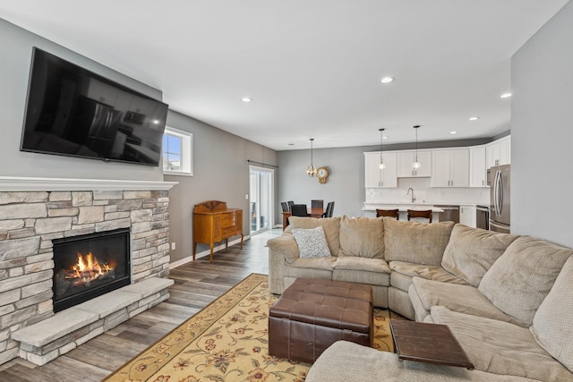 living room featuring a fireplace, sink, and wood-type flooring