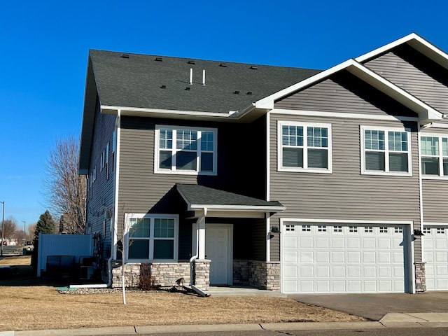 view of front of home featuring stone siding, concrete driveway, a shingled roof, and an attached garage