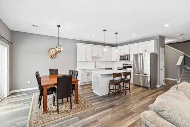 dining space with stairs, recessed lighting, baseboards, and wood finished floors