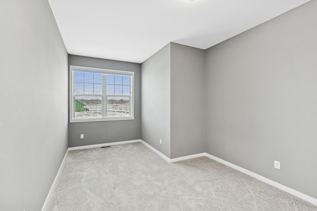 empty room featuring light carpet, visible vents, and baseboards