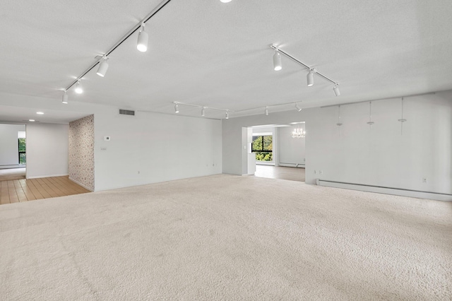 carpeted empty room with a textured ceiling and a baseboard radiator