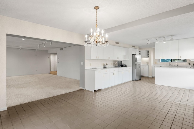 kitchen featuring white cabinetry, sink, stainless steel refrigerator with ice dispenser, a notable chandelier, and pendant lighting