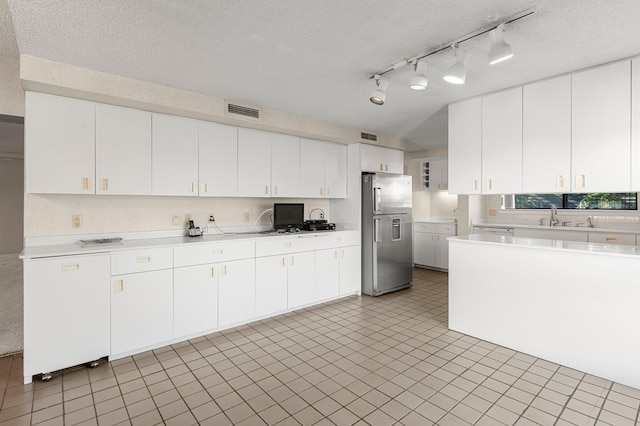 kitchen featuring stainless steel fridge with ice dispenser, a textured ceiling, and white cabinetry