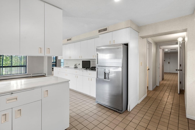 kitchen featuring white cabinets, stainless steel refrigerator with ice dispenser, and light tile patterned floors