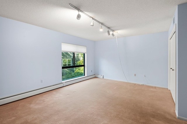 carpeted empty room featuring a textured ceiling, a baseboard radiator, and track lighting