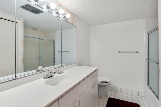 full bathroom featuring vanity, enclosed tub / shower combo, a textured ceiling, and toilet