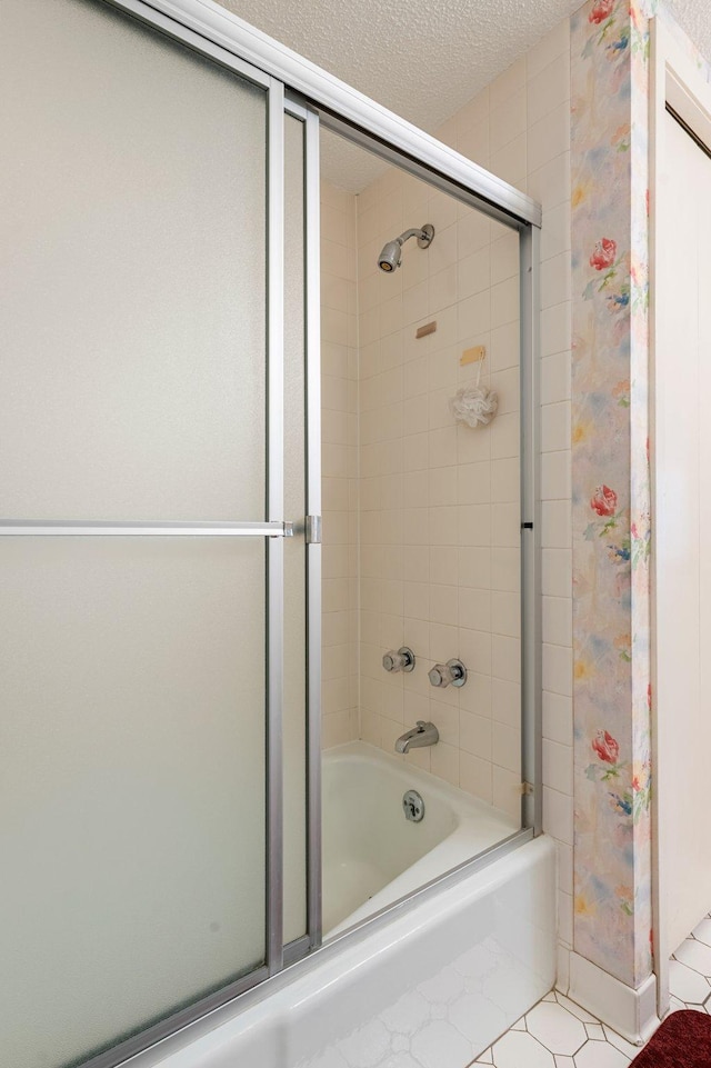 bathroom with shower / bath combination with glass door, tile patterned floors, and a textured ceiling