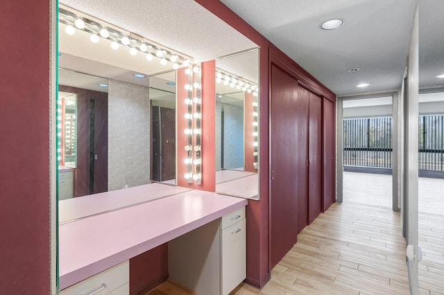 hall with light hardwood / wood-style floors and a textured ceiling